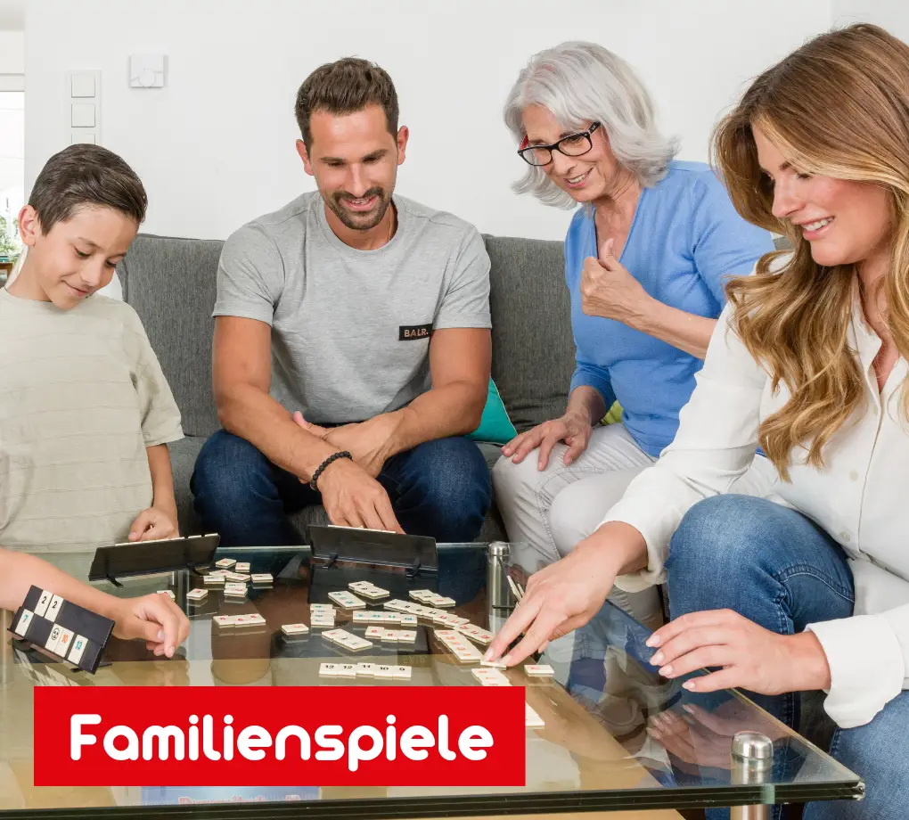 Vier Personen unterschiedlichen Alters spielen das Familienspiel Rummikub Classic