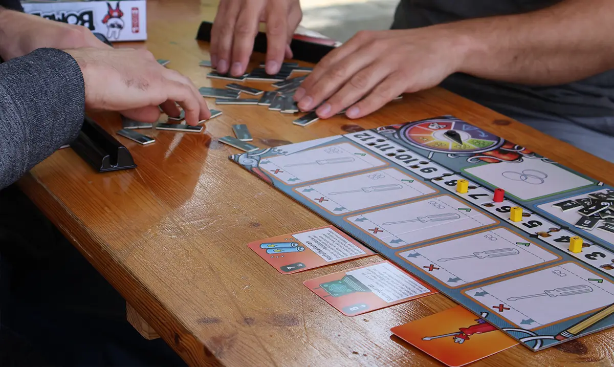 Hände von zwei Personen, die das Brettspiel Bomb Busters spielen