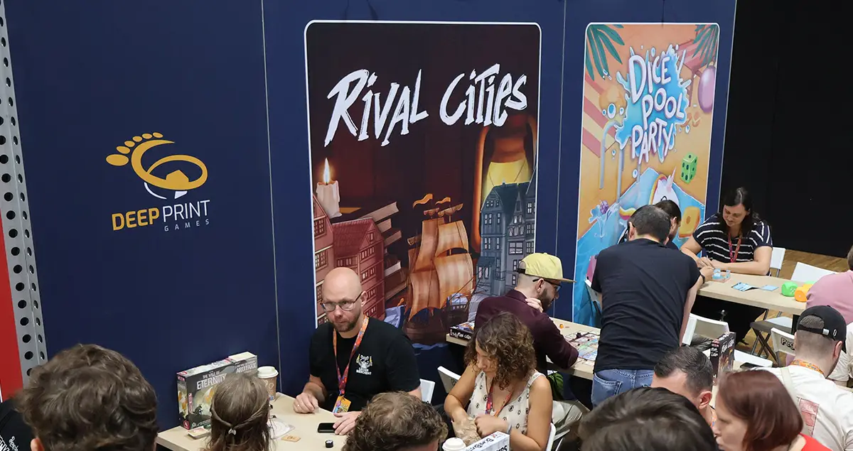 Spieltische vor einer Wand mit Illustrationen des Brettspiels Rival Cities und dem Deep Print Games Logo